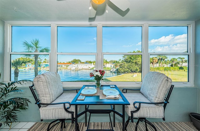 sunroom featuring ceiling fan and a water view