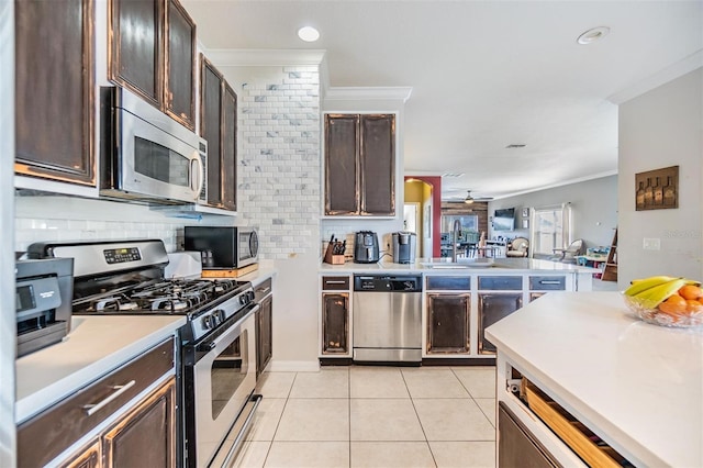 kitchen featuring light tile patterned flooring, ceiling fan, dark brown cabinetry, stainless steel appliances, and crown molding