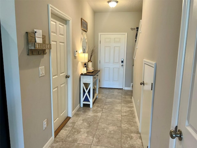 hallway with light tile patterned flooring and a textured ceiling