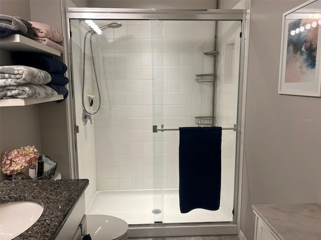 bathroom featuring vanity, a shower with door, and toilet