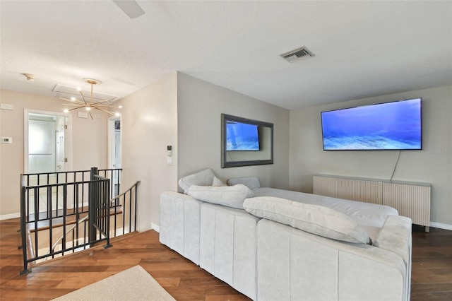 living room featuring radiator heating unit, hardwood / wood-style floors, and a notable chandelier