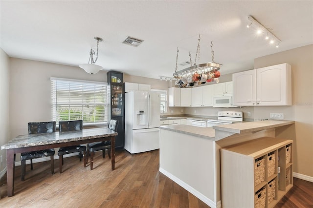 kitchen featuring pendant lighting, white cabinetry, wood-type flooring, kitchen peninsula, and white appliances