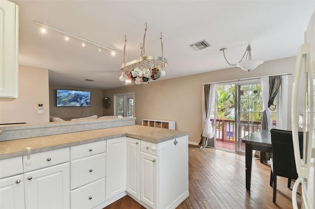 kitchen with white cabinetry, rail lighting, hardwood / wood-style floors, and kitchen peninsula