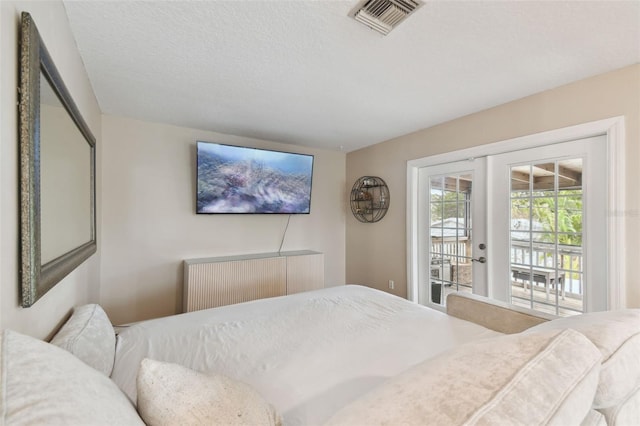 bedroom with french doors, a textured ceiling, and access to outside