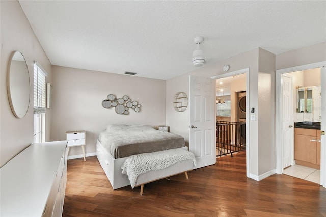 bedroom featuring hardwood / wood-style flooring, connected bathroom, and a textured ceiling