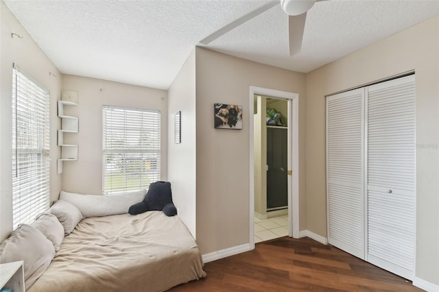 bedroom featuring hardwood / wood-style flooring, ceiling fan, connected bathroom, a textured ceiling, and a closet