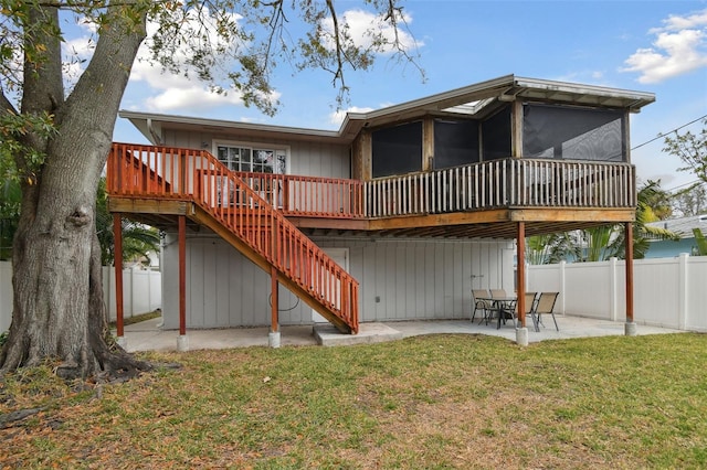 rear view of property featuring a wooden deck, a sunroom, a yard, and a patio area