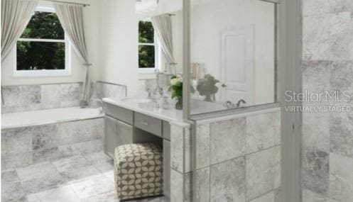 bathroom featuring tiled tub and vanity