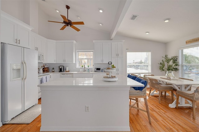 kitchen featuring white cabinetry, a center island, and white appliances