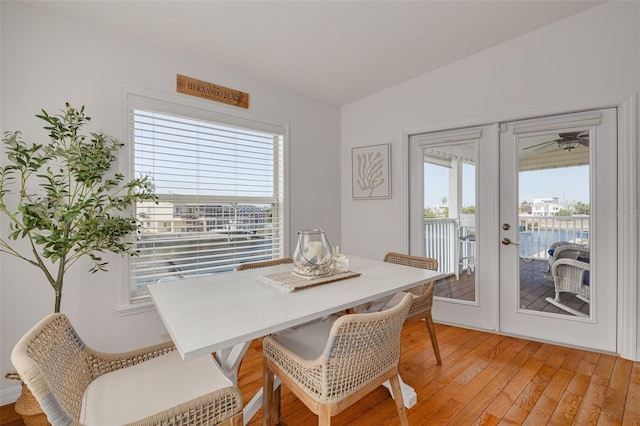 dining space with french doors, a water view, and light wood-type flooring