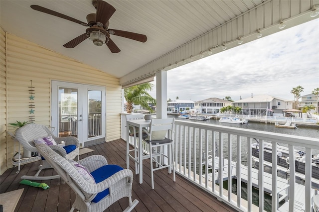 wooden deck featuring a water view, ceiling fan, and french doors