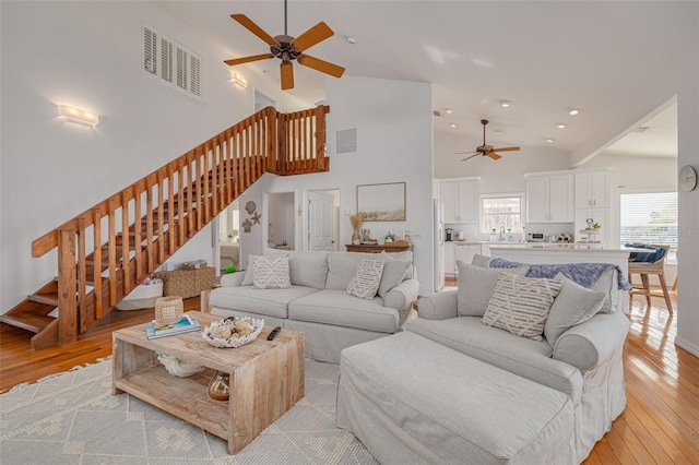 living room featuring light hardwood / wood-style flooring, high vaulted ceiling, and ceiling fan