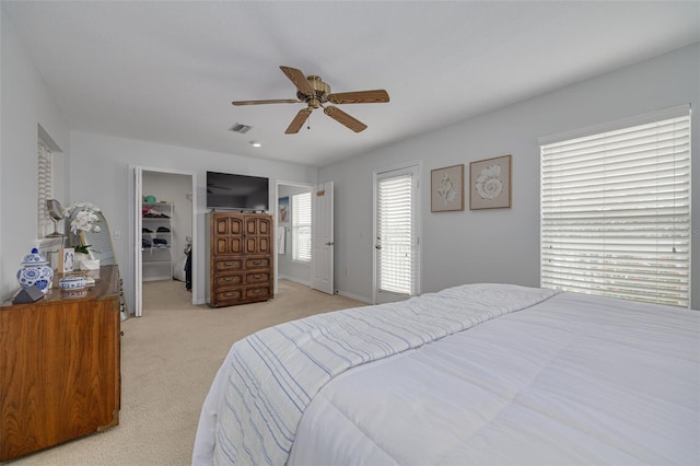 bedroom featuring light carpet, a spacious closet, a closet, and ceiling fan