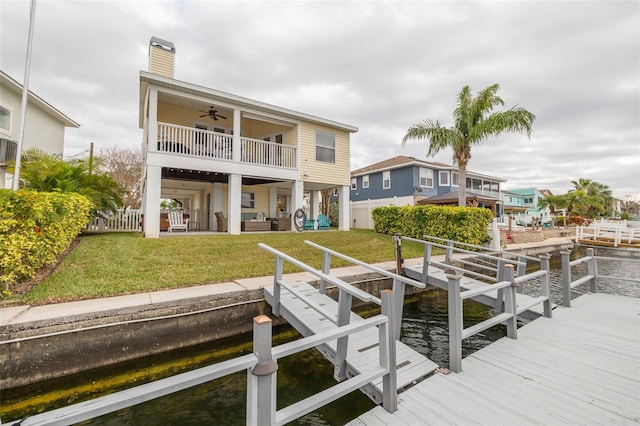 rear view of house featuring a water view, ceiling fan, an outdoor hangout area, and a lawn