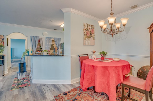 dining space with crown molding, a chandelier, and light wood-type flooring