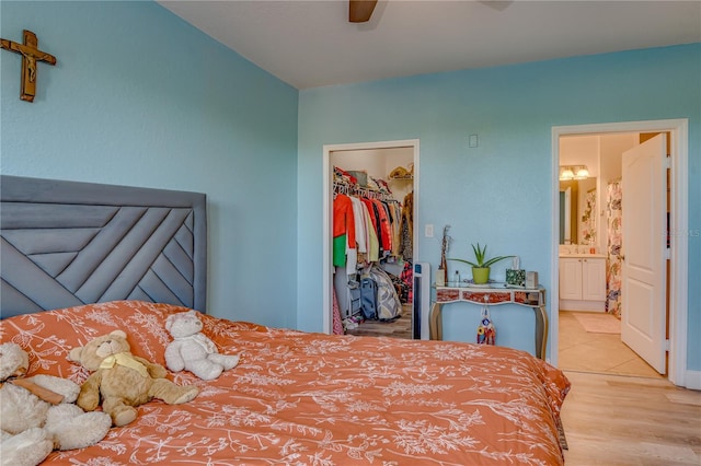 bedroom featuring ensuite bath, ceiling fan, light hardwood / wood-style floors, a walk in closet, and a closet