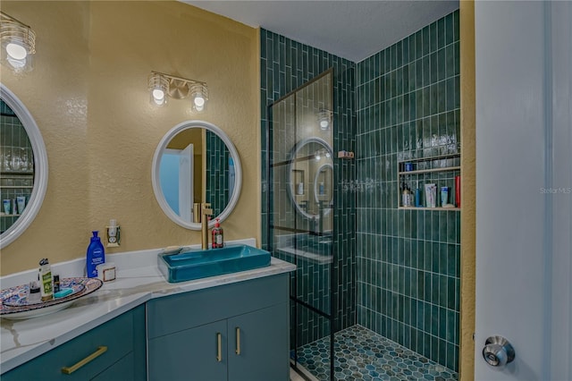 bathroom with a tile shower and vanity