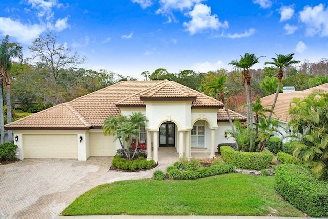 mediterranean / spanish house featuring a garage, a front yard, and french doors