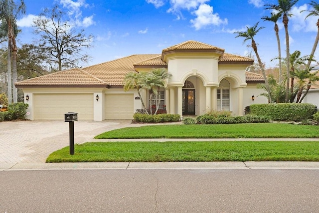 mediterranean / spanish-style house with a garage and a front lawn