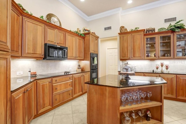 2867 Grey Oaks Blvd, Tarpon Springs, FL 34688 - kitchen with a kitchen island, light tile patterned floors, dark stone counters, and black appliances