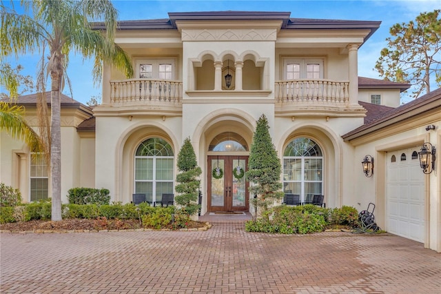 mediterranean / spanish home featuring a garage, a balcony, and french doors