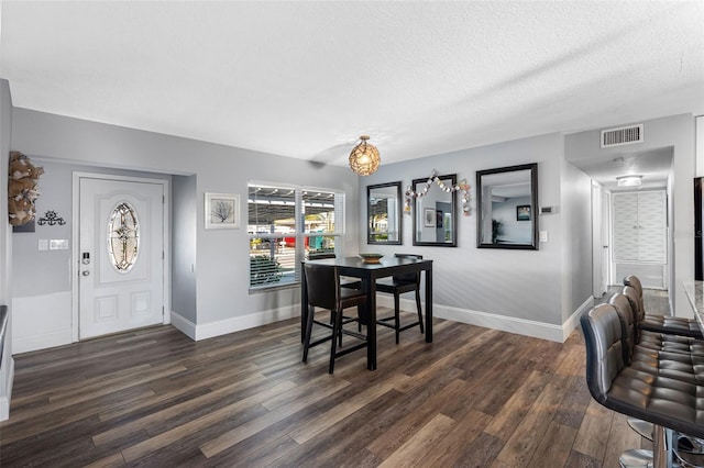 dining space featuring dark wood-type flooring and a textured ceiling