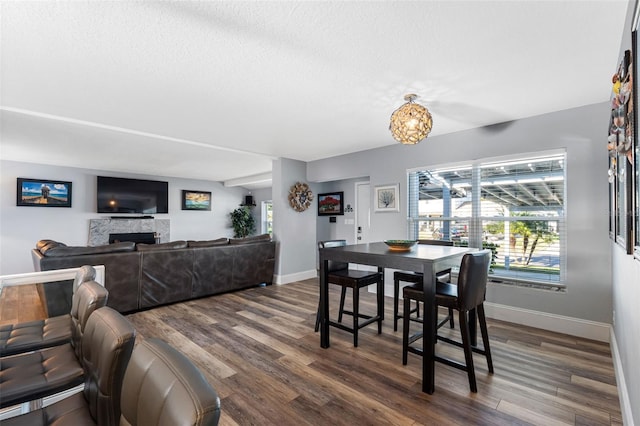 dining area featuring a fireplace, dark hardwood / wood-style flooring, a textured ceiling, and a notable chandelier