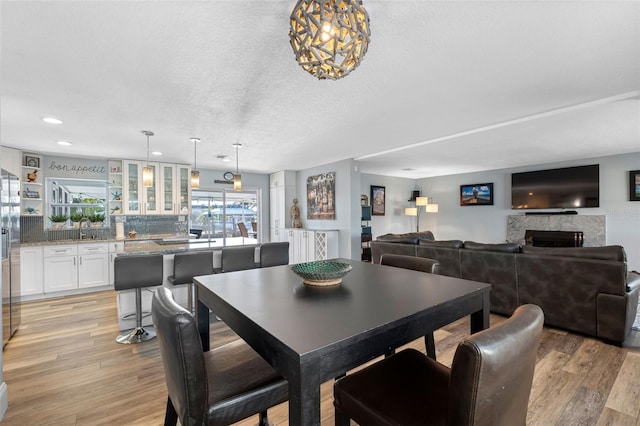 dining space featuring sink, a textured ceiling, and light wood-type flooring