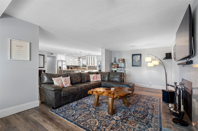 living room with hardwood / wood-style flooring, a fireplace, and a textured ceiling