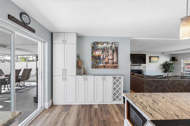 kitchen with white cabinetry, light hardwood / wood-style flooring, and light stone countertops