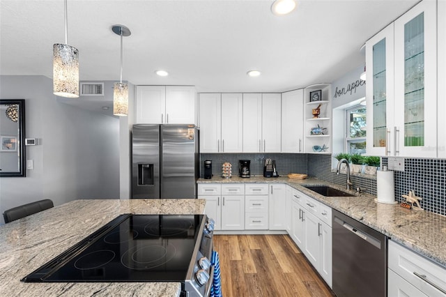 kitchen featuring sink, hanging light fixtures, stainless steel appliances, decorative backsplash, and white cabinets