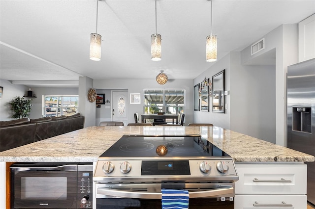 kitchen with white cabinetry, light stone counters, decorative light fixtures, and stainless steel appliances