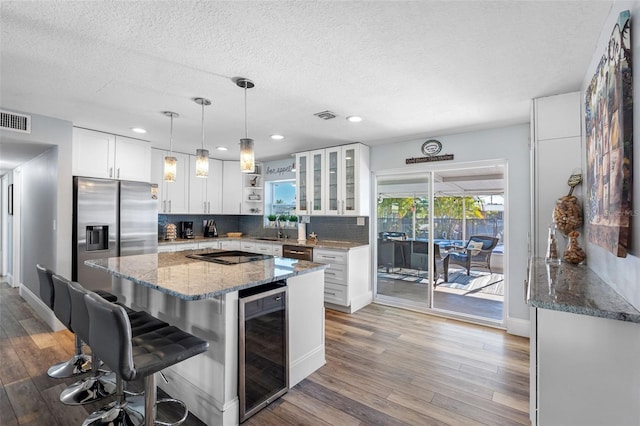 kitchen with stainless steel fridge, white cabinetry, wine cooler, a kitchen bar, and decorative backsplash