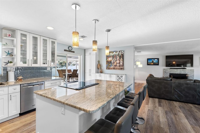 kitchen featuring white cabinetry, hanging light fixtures, stainless steel dishwasher, a kitchen breakfast bar, and a kitchen island