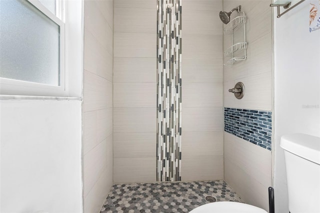 bathroom featuring a tile shower and toilet