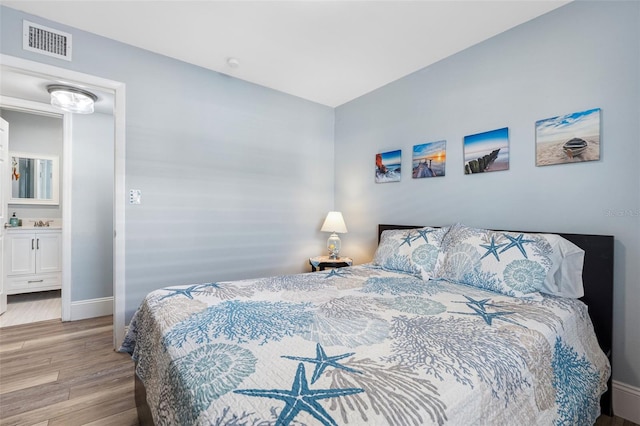 bedroom featuring light hardwood / wood-style floors and ensuite bath