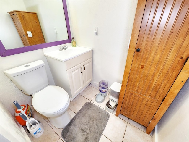 half bathroom featuring tile patterned flooring, vanity, and toilet