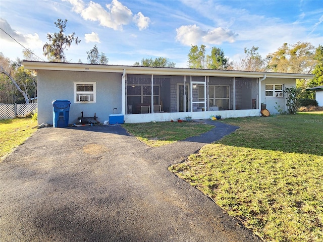 rear view of property featuring a sunroom, a lawn, and stucco siding