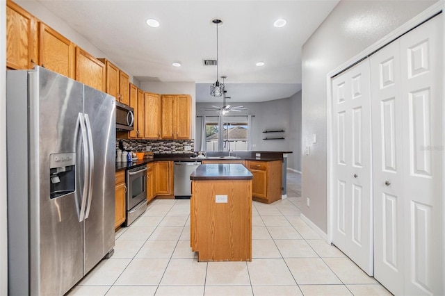 kitchen featuring stainless steel appliances, a kitchen island, hanging light fixtures, and light tile patterned floors