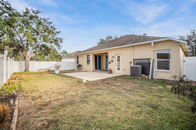 rear view of house featuring a yard, central AC unit, and a patio area