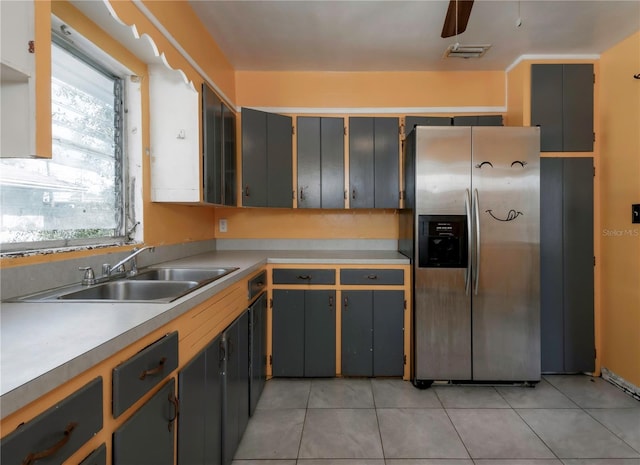 kitchen with stainless steel fridge, gray cabinets, sink, and light tile patterned floors