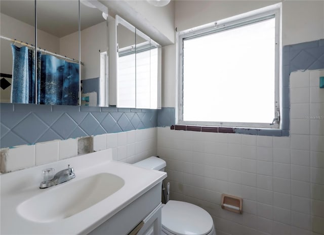 bathroom featuring vanity, tile walls, and toilet