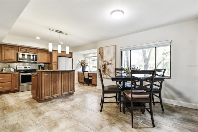 kitchen with appliances with stainless steel finishes, hanging light fixtures, and backsplash