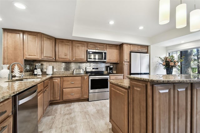 kitchen featuring appliances with stainless steel finishes, pendant lighting, tasteful backsplash, sink, and light stone counters