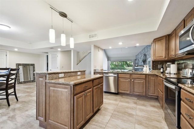 kitchen featuring decorative light fixtures, a center island, appliances with stainless steel finishes, kitchen peninsula, and light stone countertops