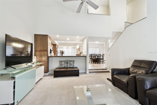 carpeted living room with a towering ceiling and ceiling fan