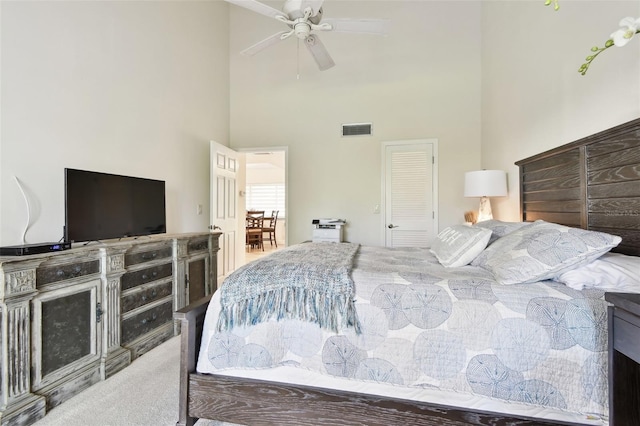 bedroom featuring a towering ceiling, ceiling fan, and carpet flooring