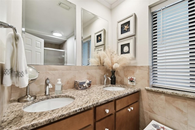 bathroom with tile walls, vanity, crown molding, and a shower with door