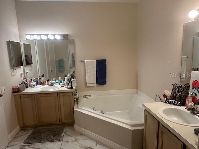 bathroom featuring vanity and tiled bath