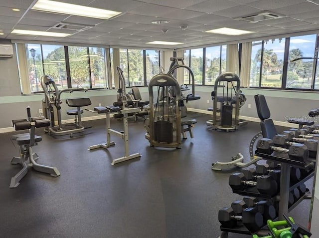 gym featuring a wall mounted AC and a drop ceiling